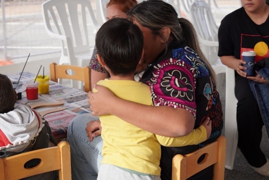 A woman puts her arm around a child at an art class