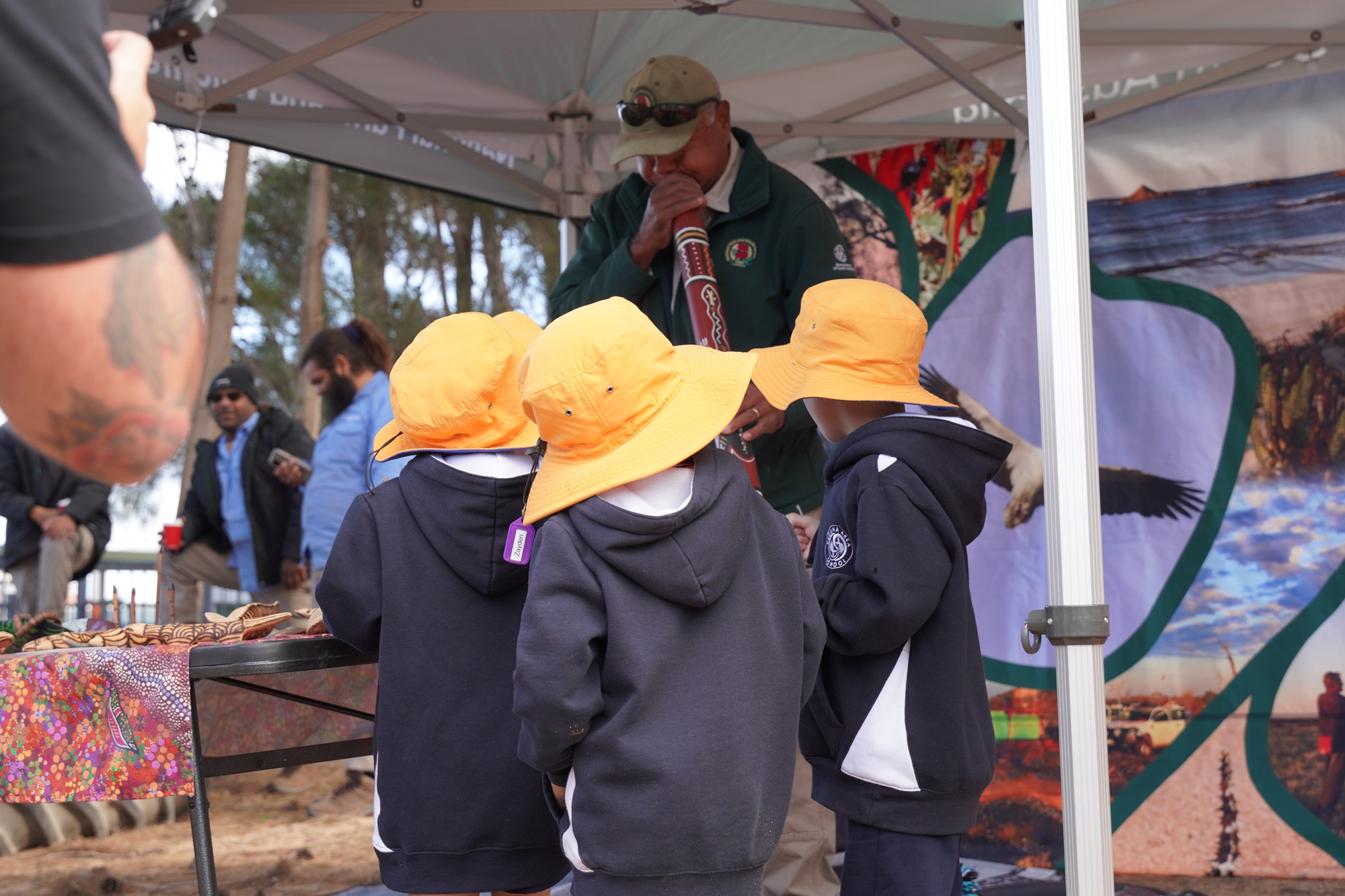 A man plays a didgeridoo to 3 children