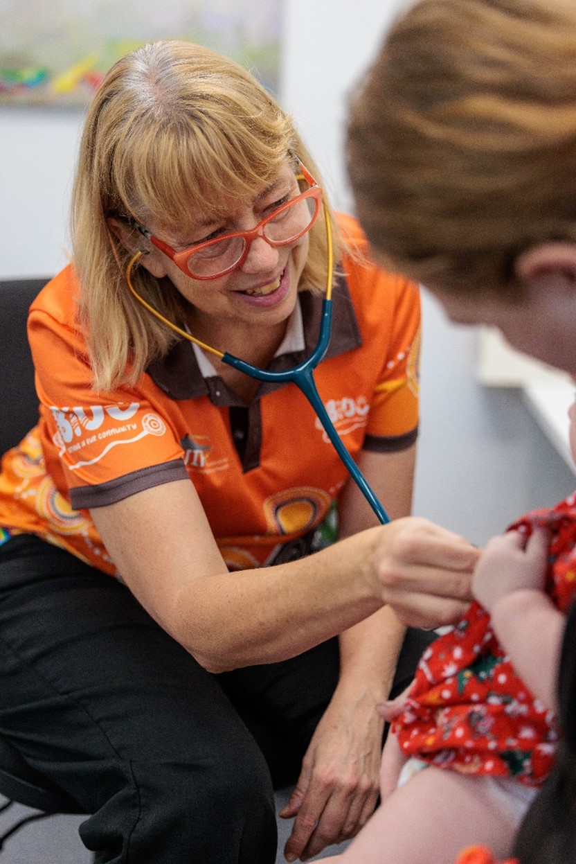 A Female Doctor holds a stethoscope to a pregnant woman